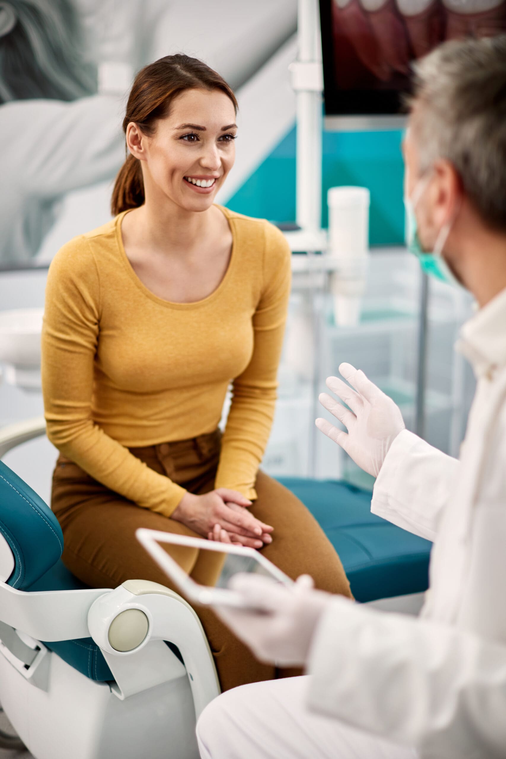 Young happy woman talking to her dentist at dental clinic.